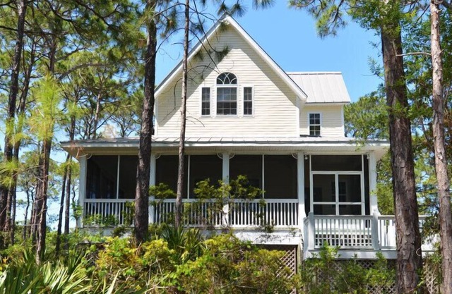 This sweet cottage is fenced by lush, natural landscaping and offers a peek of the Apalachicola Bay.